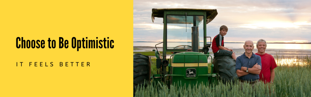 Image of three generation family near tractor in PEI field with text "Choose to be optimistic. It feels better." 