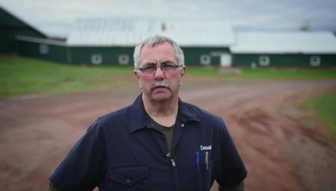 Image of farmer Donald in front of barns
