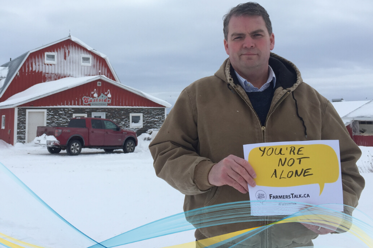 Image of Minister Bloyce Thompson in front of his barn holding a FarmersTalk promo that reads "You are Not Alone"