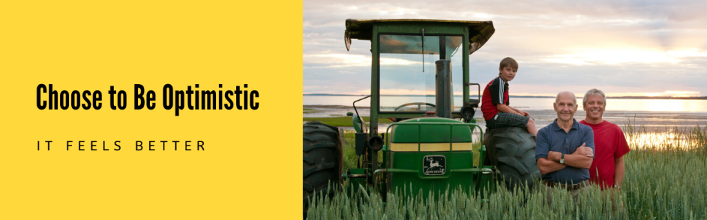 Image of three generation family near tractor in PEI field with text "Choose to be optimistic. It feels better."